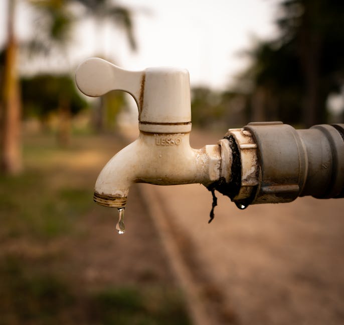 A close-up shot of a water droplet falling from an outdoor tap, highlighting water conservation issues.